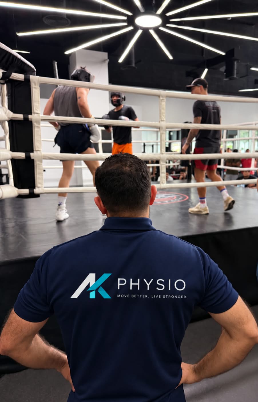 AK PHYSIO physiotherapist in AK PHYSIO polo overseeing athletes training at a boxing ring